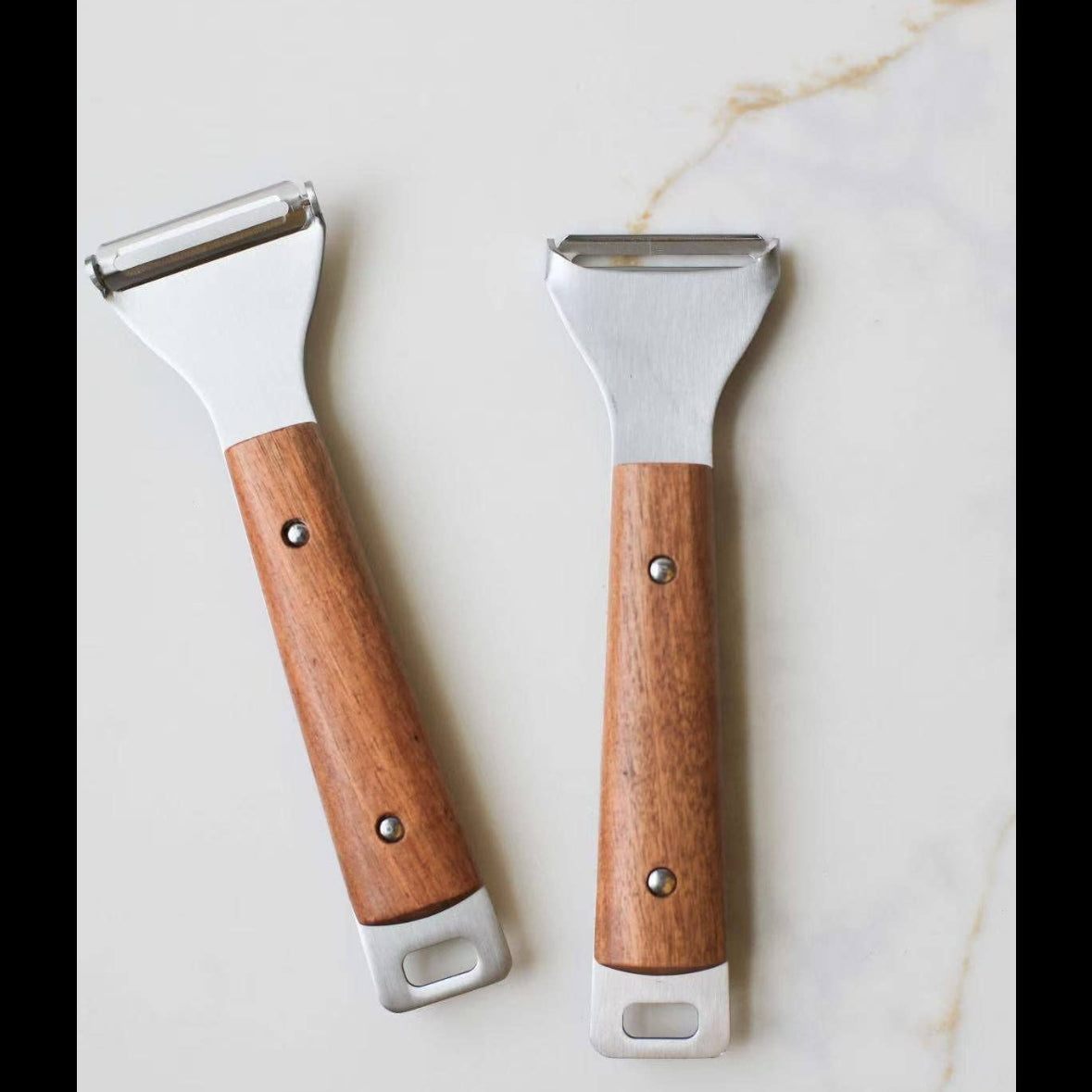 Two kitchen scrapers with wooden handles on a marble surface