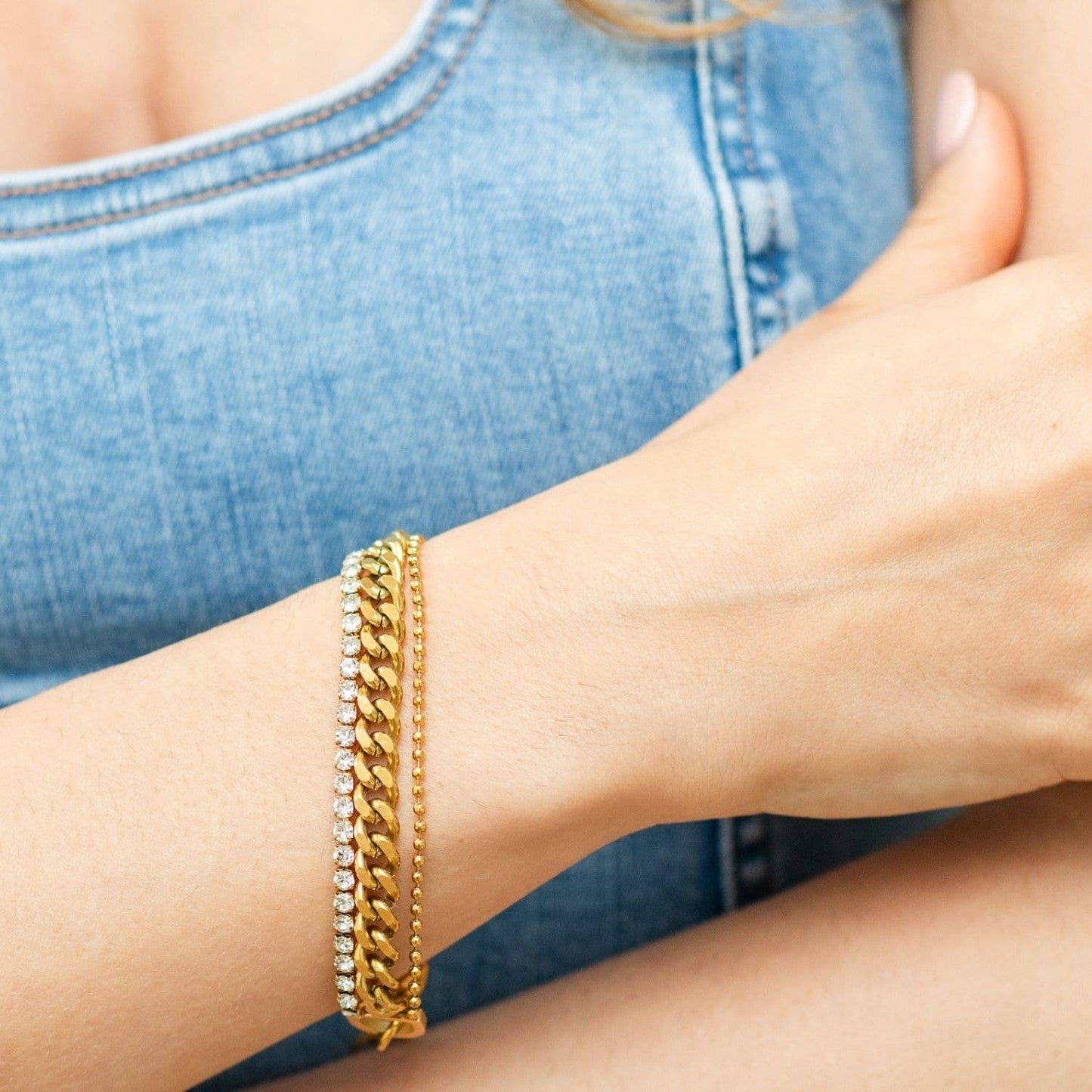 Gold bracelet on a wrist with denim background