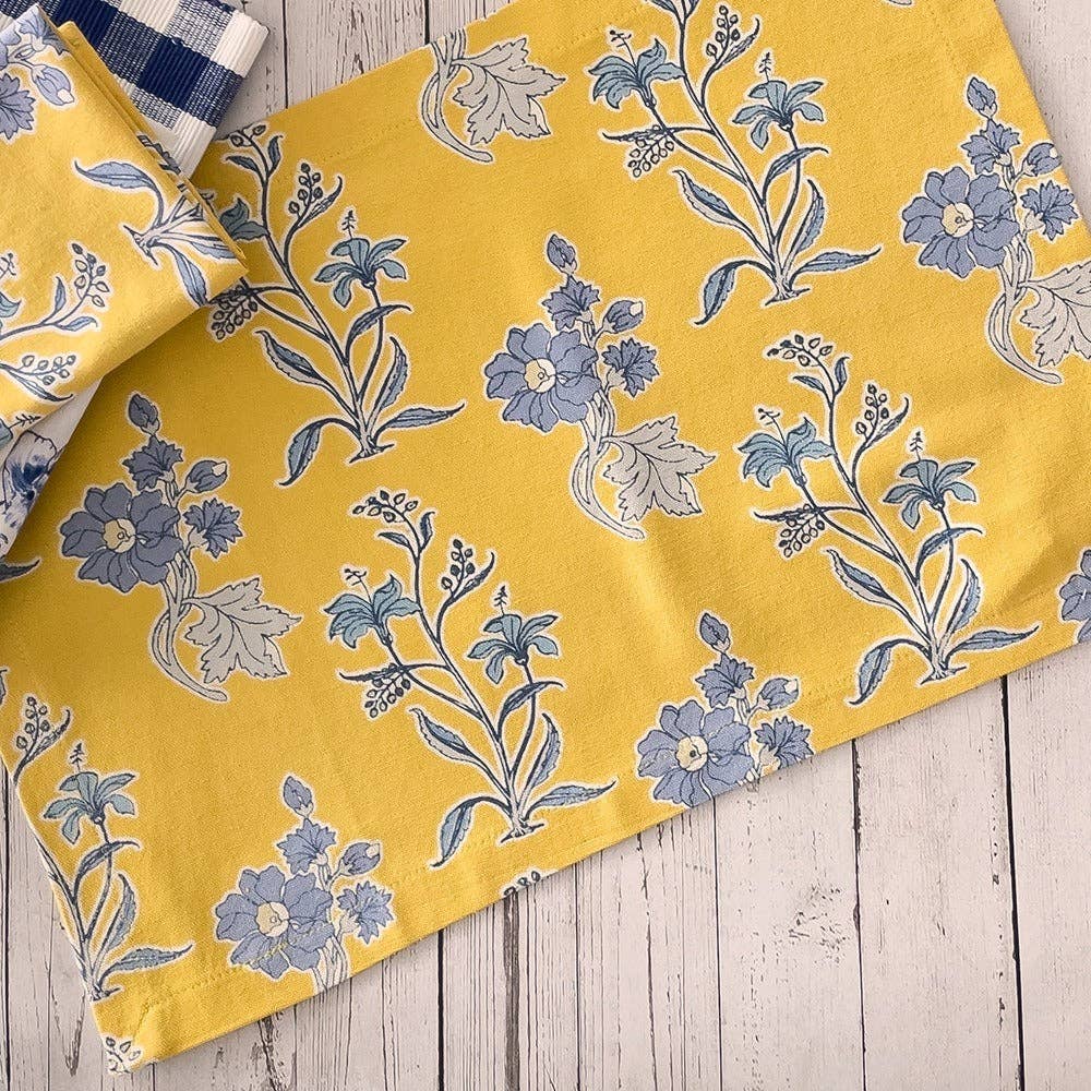 Yellow fabric with blue floral pattern on a wooden surface