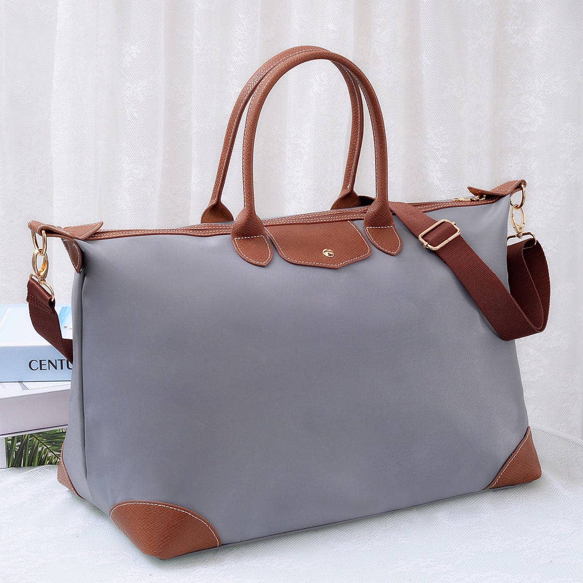 Gray handbag with brown handles and strap on a white background