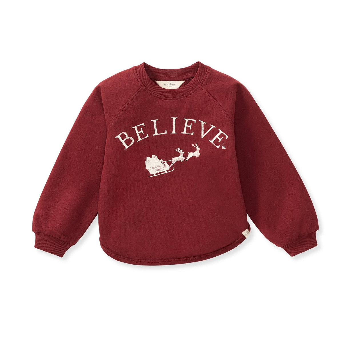 A kids' long-sleeve sweatshirt in deep burgundy red, featuring a white graphic print on the front with the word 'BELIEVE' in an arched font above an illustration of Santa Claus in a sleigh pulled by reindeer. The sweatshirt is displayed flat against a solid white background.