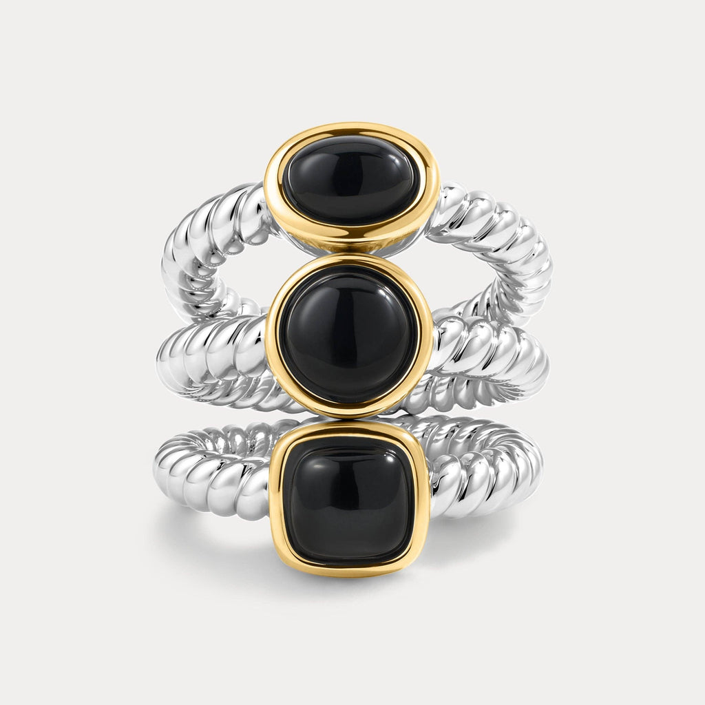 Three stacked rings with black gemstones and gold and silver bands on a light gray background