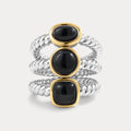 Three stacked rings with black gemstones and gold and silver bands on a light gray background