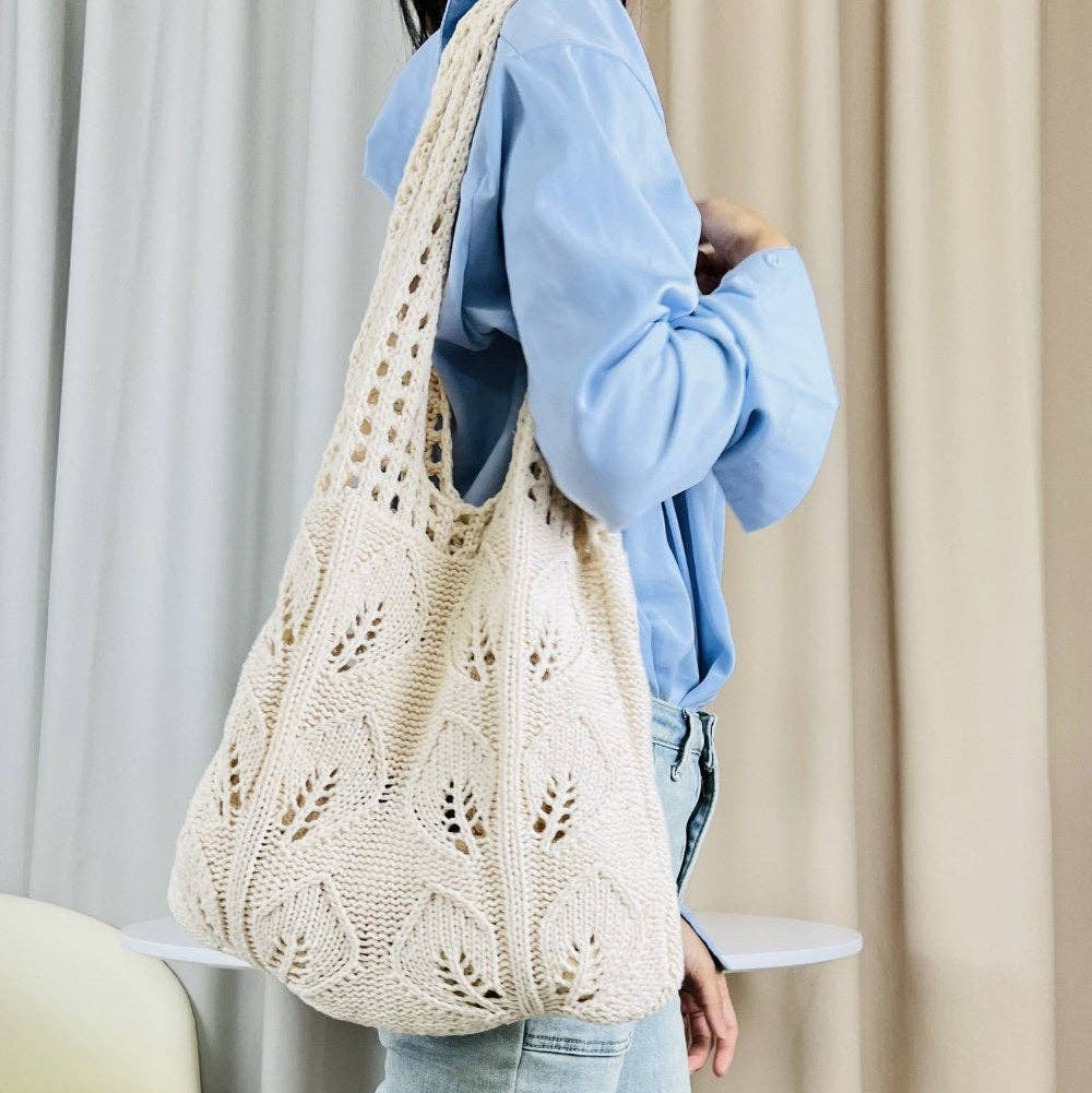 Person holding a beige crochet bag against a neutral background