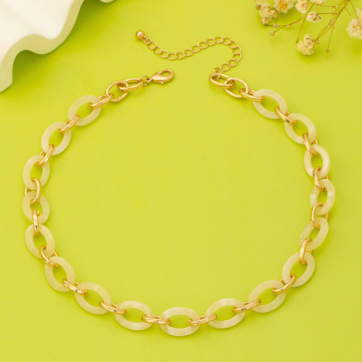 Gold and beige chain necklace on a green background