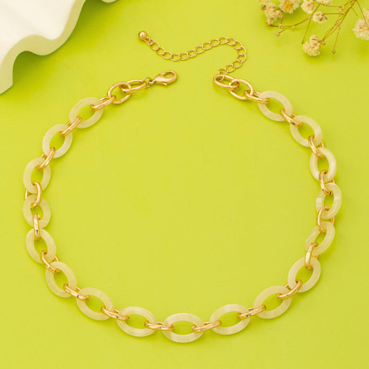 Gold and beige chain necklace on a green background