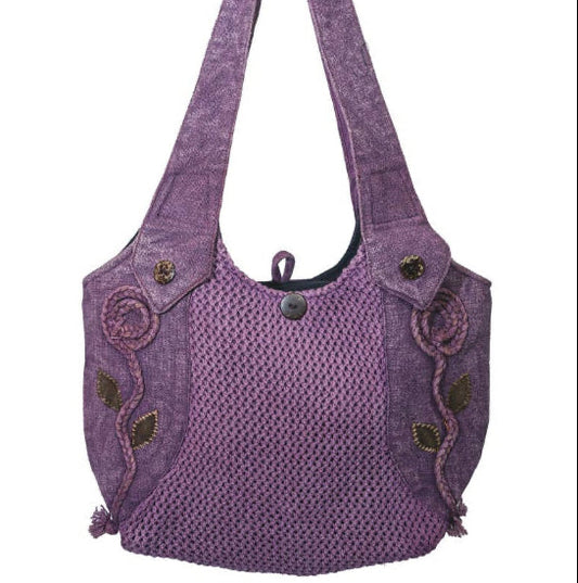 A purple woven shoulder bag with a textured body, decorative embroidered swirls and leaf motifs on the sides, and a single shoulder strap, shown against a plain white background.