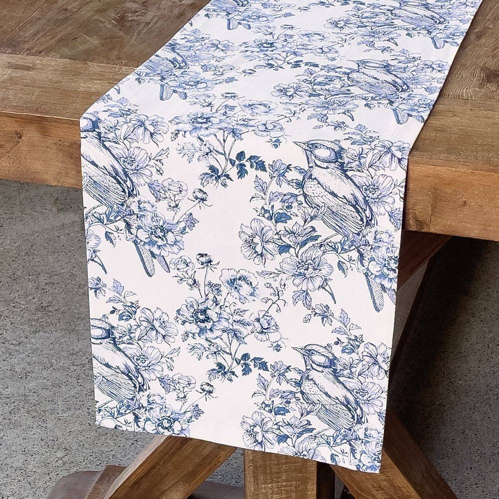 Table runner with blue floral and bird pattern on a wooden table