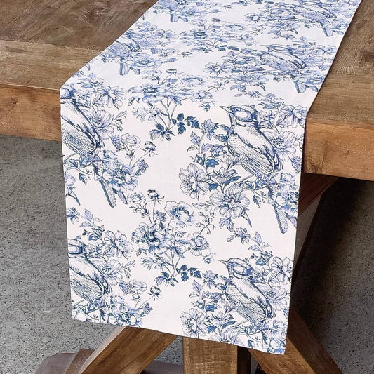 Table runner with blue floral and bird pattern on a wooden table