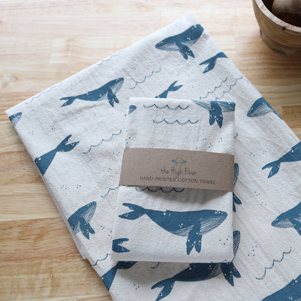 Folded towel with whale pattern on a wooden surface