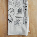 White towel with black line art designs of dogs on a wooden surface