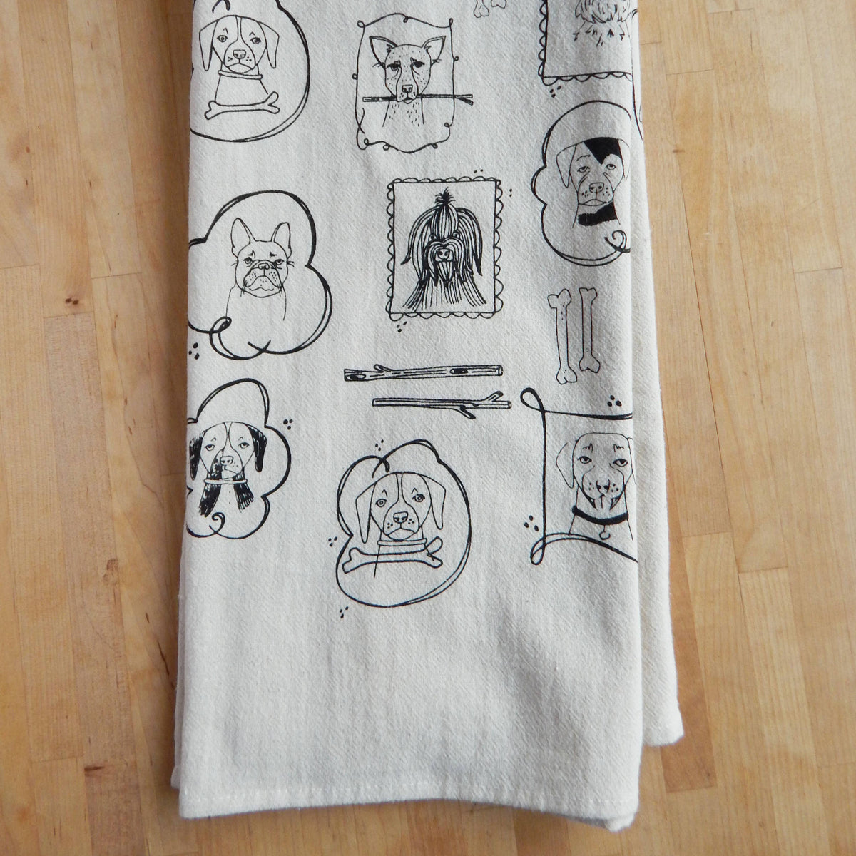 White towel with black line art designs of dogs on a wooden surface