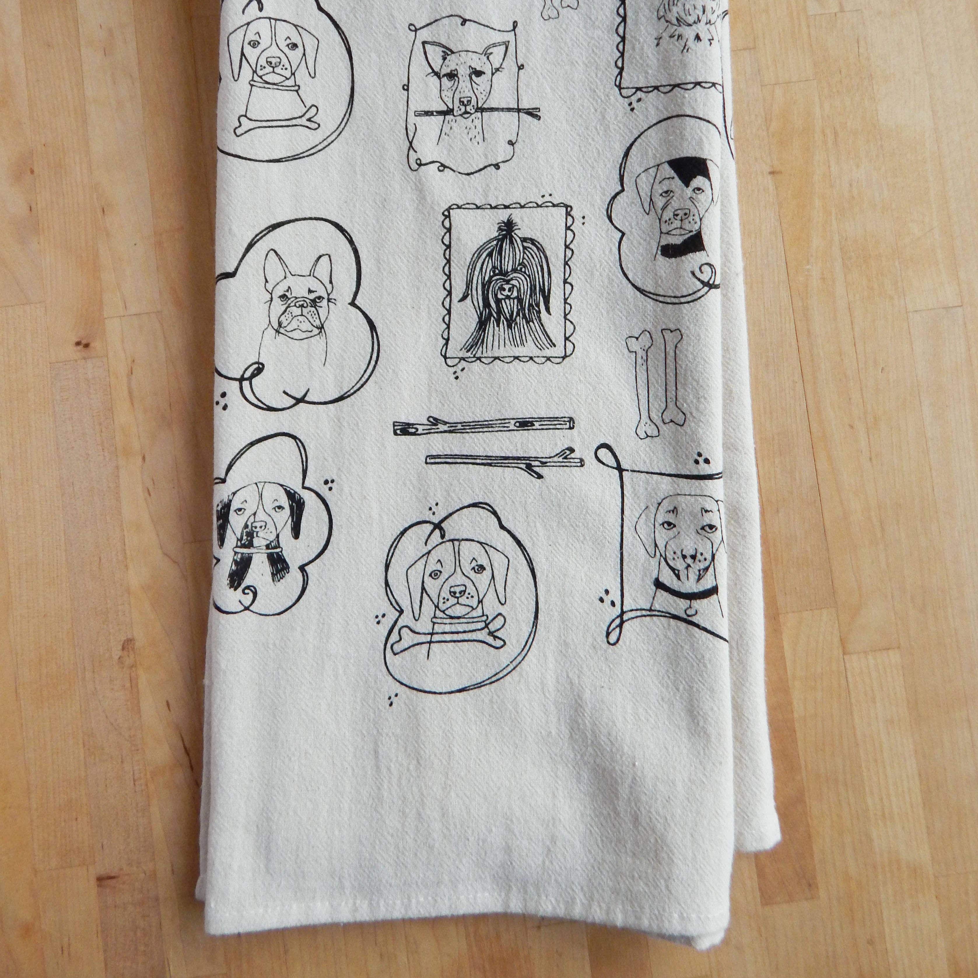 White towel with black line art designs of dogs on a wooden surface