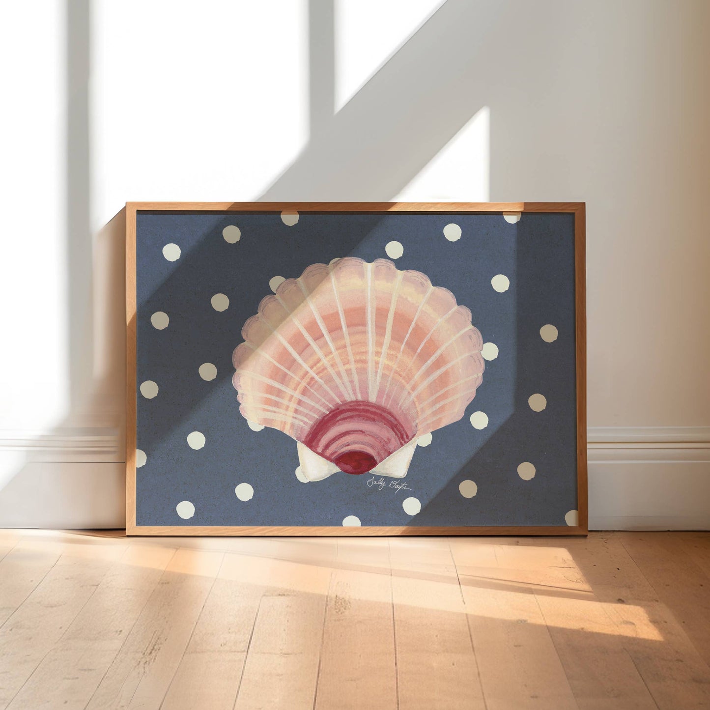 Framed artwork of a shell on a polka dot background in a sunlit room.