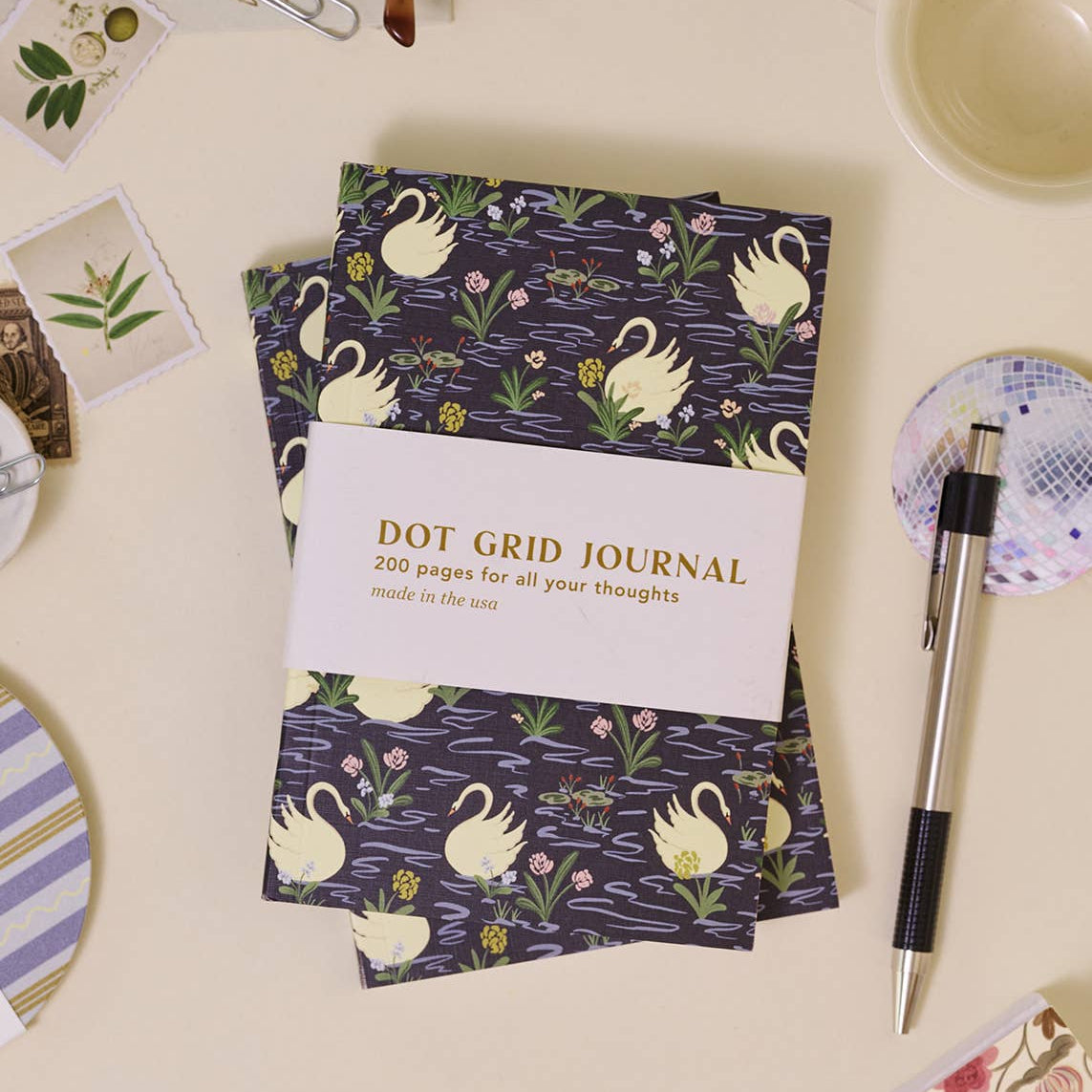 Dot grid journal with swan design on a desk with stationery items