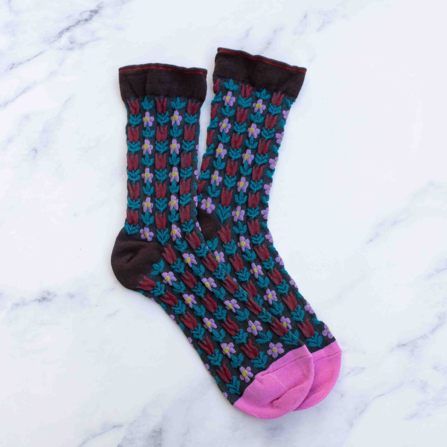 Colorful patterned socks with pink toes on a white marble background
