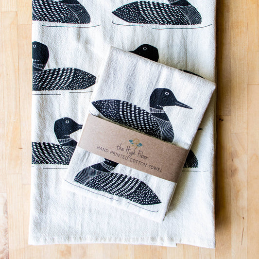 Set of tea towels with loon designs on a wooden surface