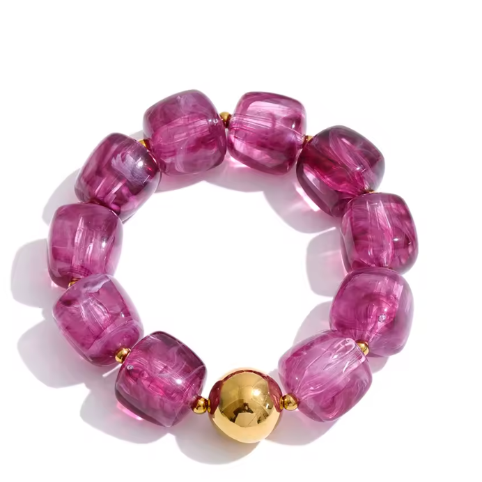 A beaded stretch bracelet featuring chunky, translucent magenta-purple beads and a central shiny gold ball accent, displayed on a clean white background.
