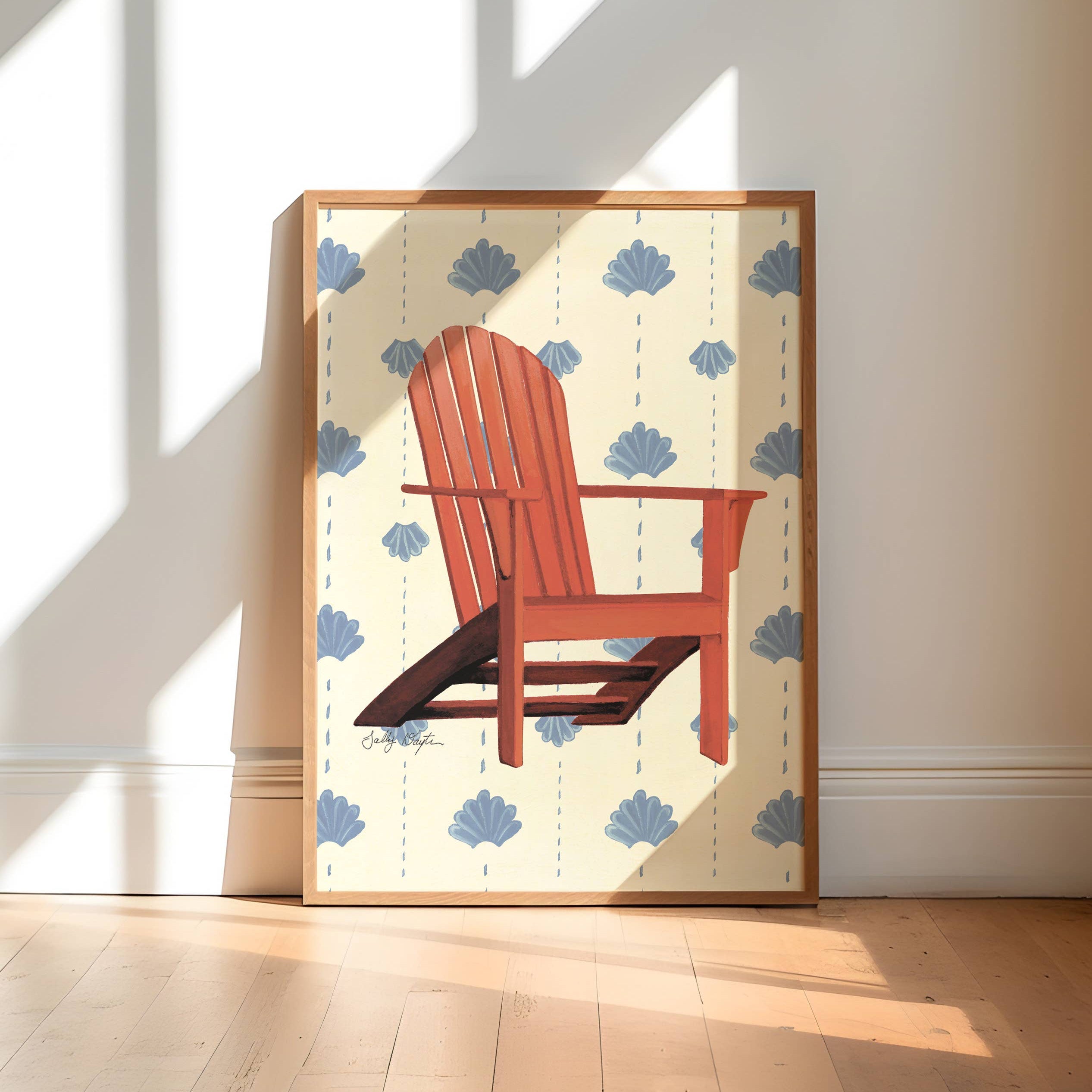 Framed artwork of a red chair on a white background with blue flowers, displayed in a sunlit room.