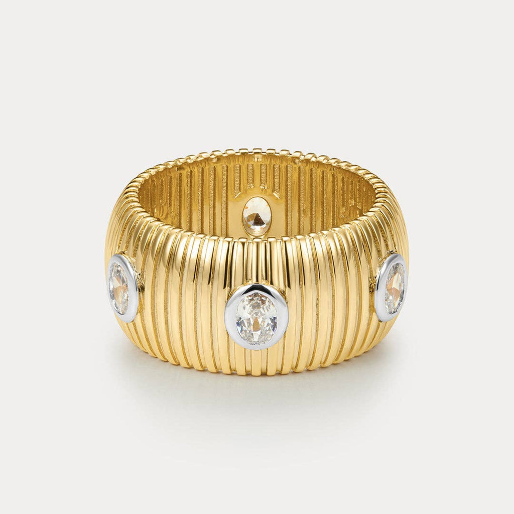 Gold ring with diamond-like stones on a light gray background