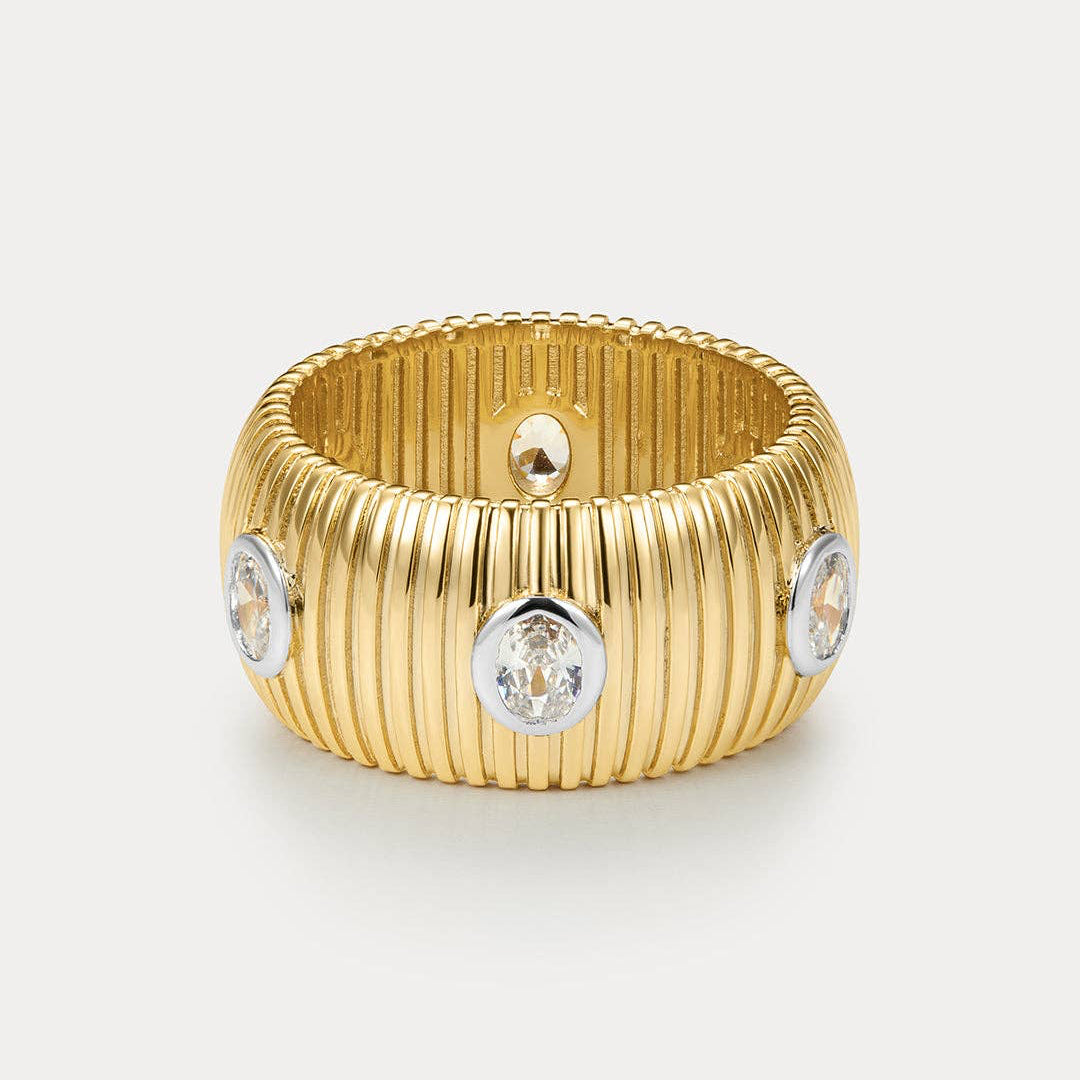 Gold ring with diamond-like stones on a light gray background