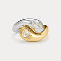 Two-tone gold and silver ring with clear gemstones on a light gray background