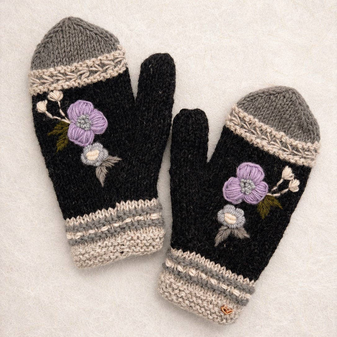 Pair of black mittens with floral embroidery on a light background