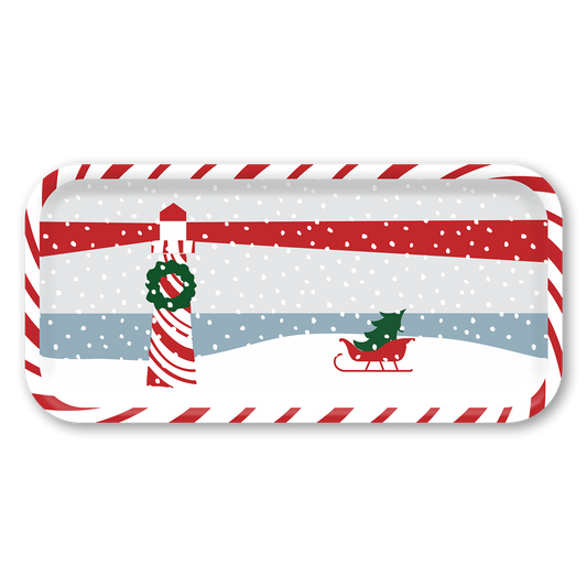 A rectangular holiday-themed tray with a white border and a printed winter scene featuring a red-and-white lighthouse, falling snow, a red sleigh, and a green Christmas tree, shown on a plain white background.