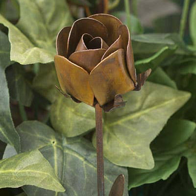 Bronze rose flower sculpture among green leaves