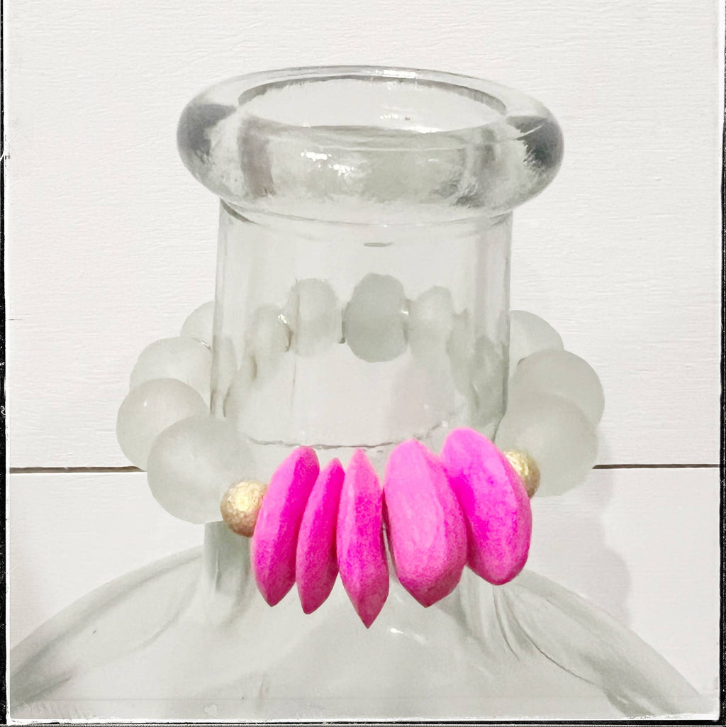 Pink beaded bracelet on a clear glass bottle with white beads