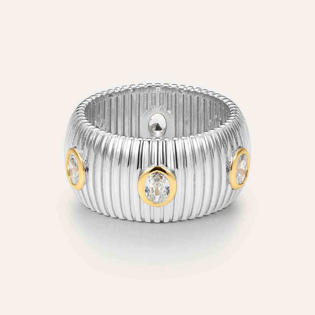 Silver ring with gold accents and embedded diamonds on a light gray background