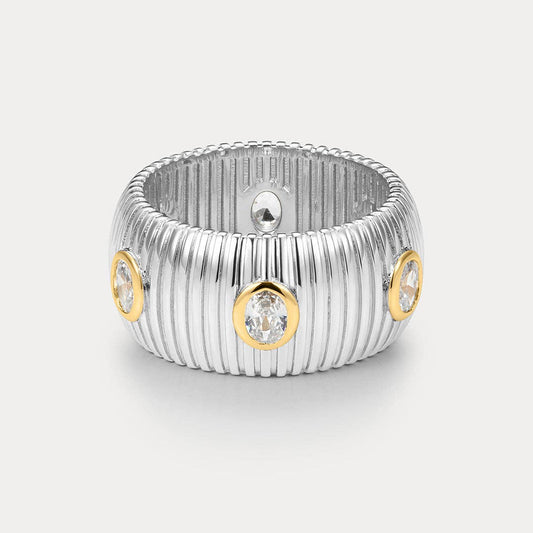 Silver ring with gold accents and embedded diamonds on a light gray background