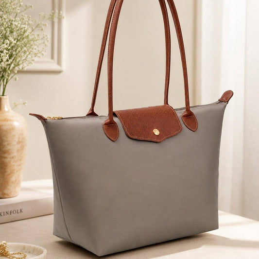 Gray handbag with brown handles on a light surface