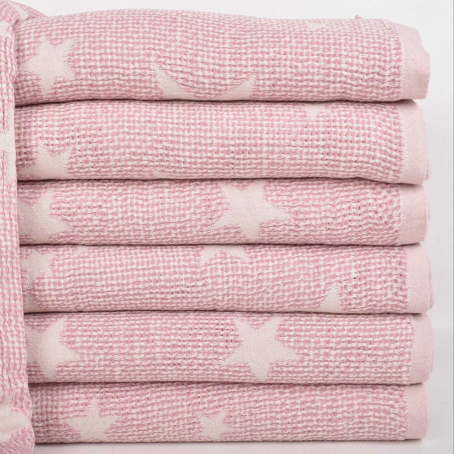 A stack of folded pink textured towels with white star patterns, shown on a clean white background.