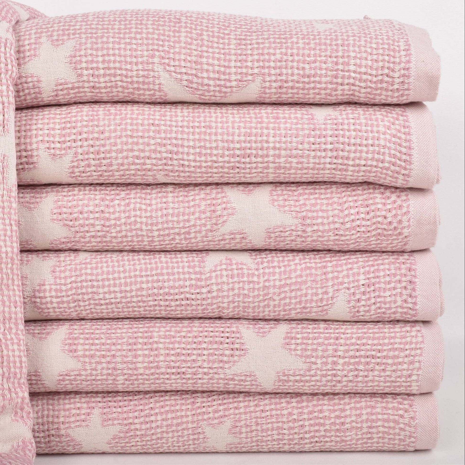 A stack of folded pink textured towels with white star patterns, shown on a clean white background.