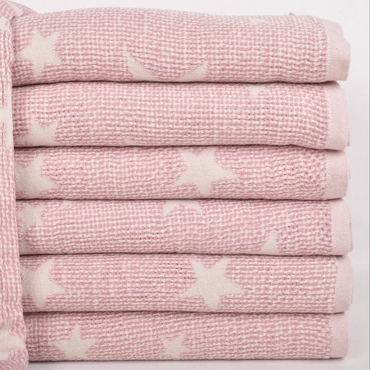 A stack of folded pink textured towels with white star patterns, shown on a clean white background.
