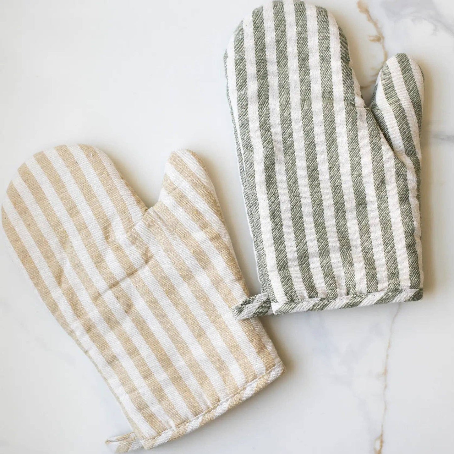 Pair of striped oven mitt and pot holder on a white marble surface
