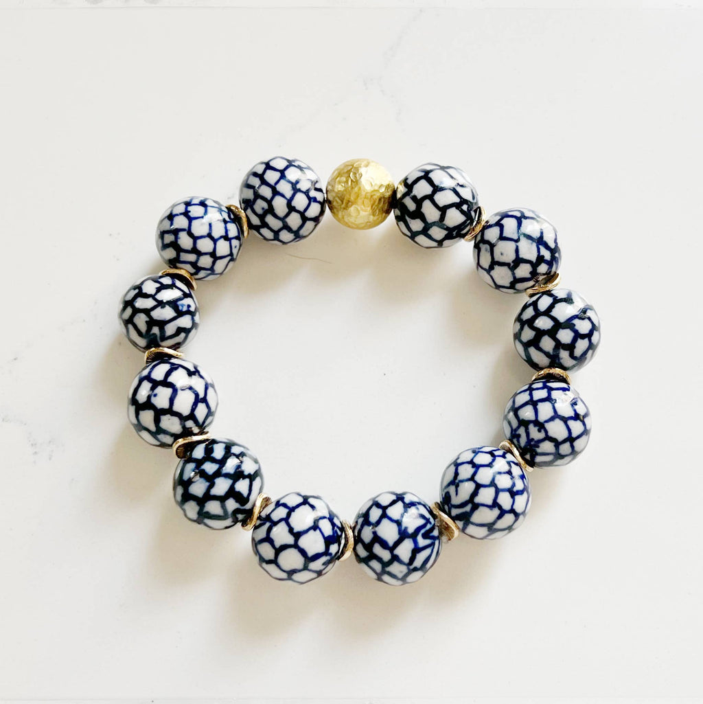 Bracelet with blue and white patterned beads and a gold accent on a light background