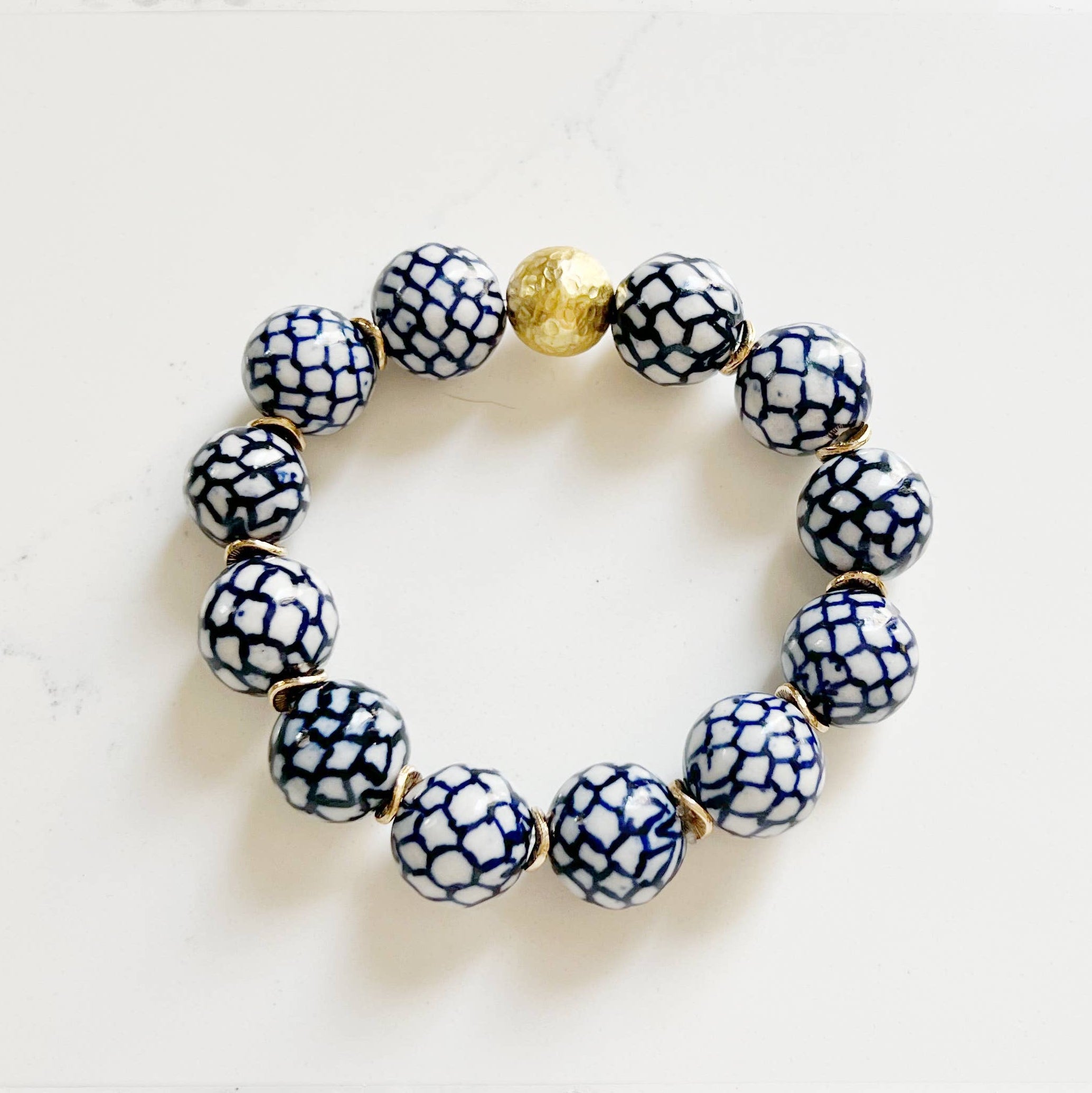 Bracelet with blue and white patterned beads and a gold accent on a light background