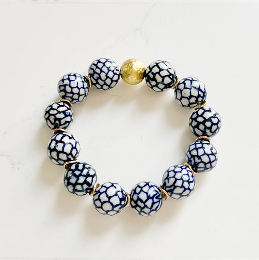 Bracelet with blue and white patterned beads and a gold accent on a light background
