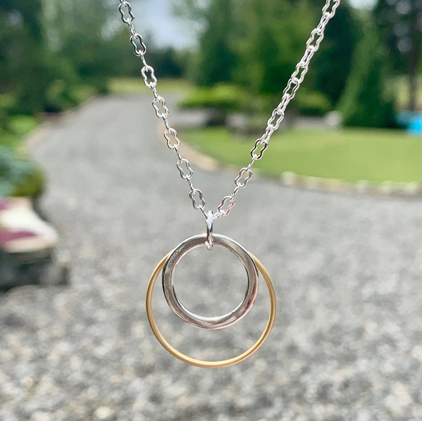 Necklace with a double-circle pendant on a blurred outdoor background