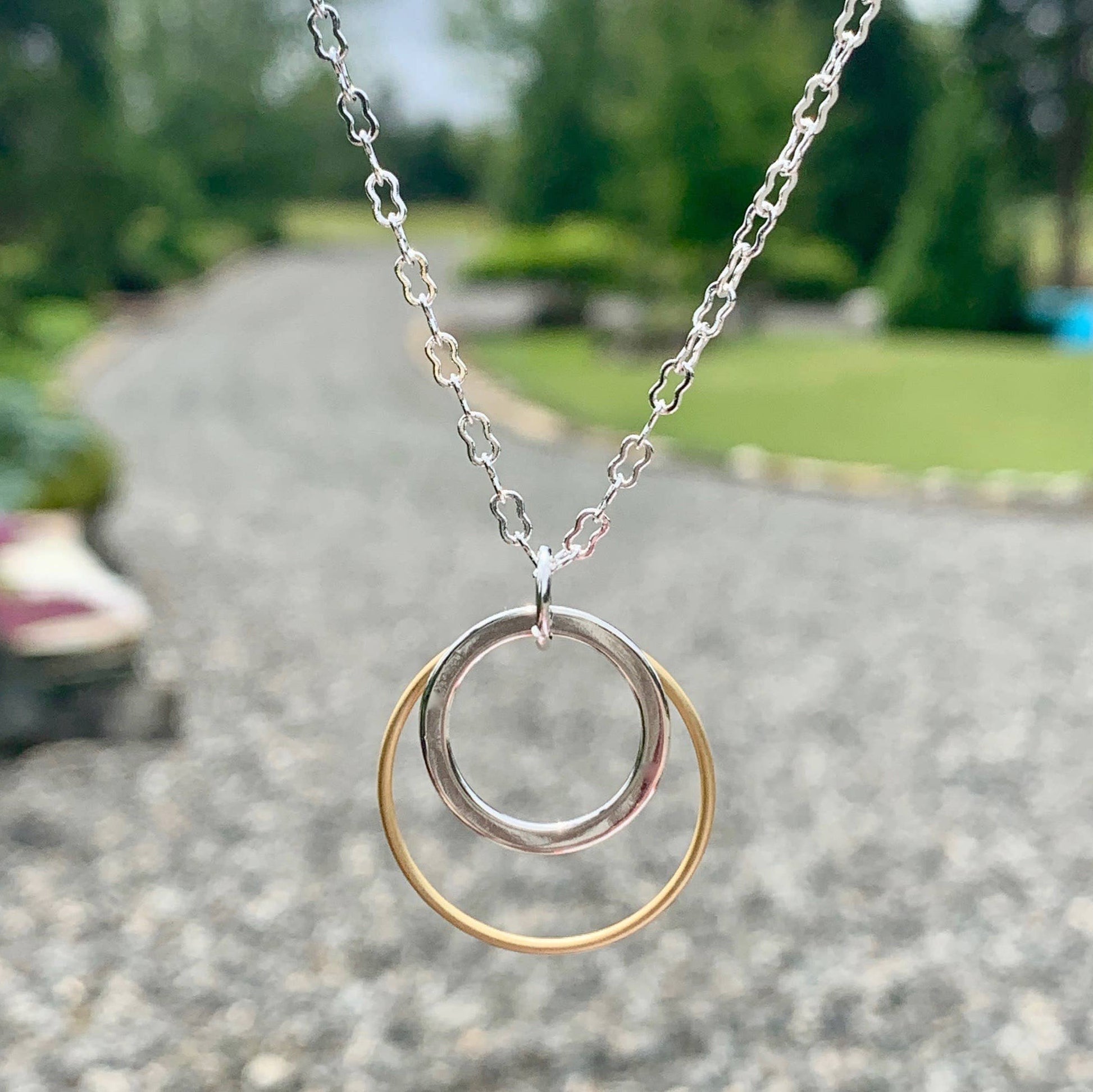 Necklace with a double-circle pendant on a blurred outdoor background