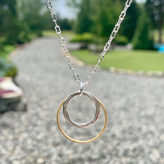 Necklace with a double-circle pendant on a blurred outdoor background