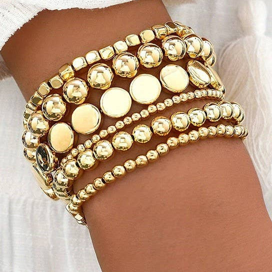 Gold beaded bracelet on a wrist with a white background